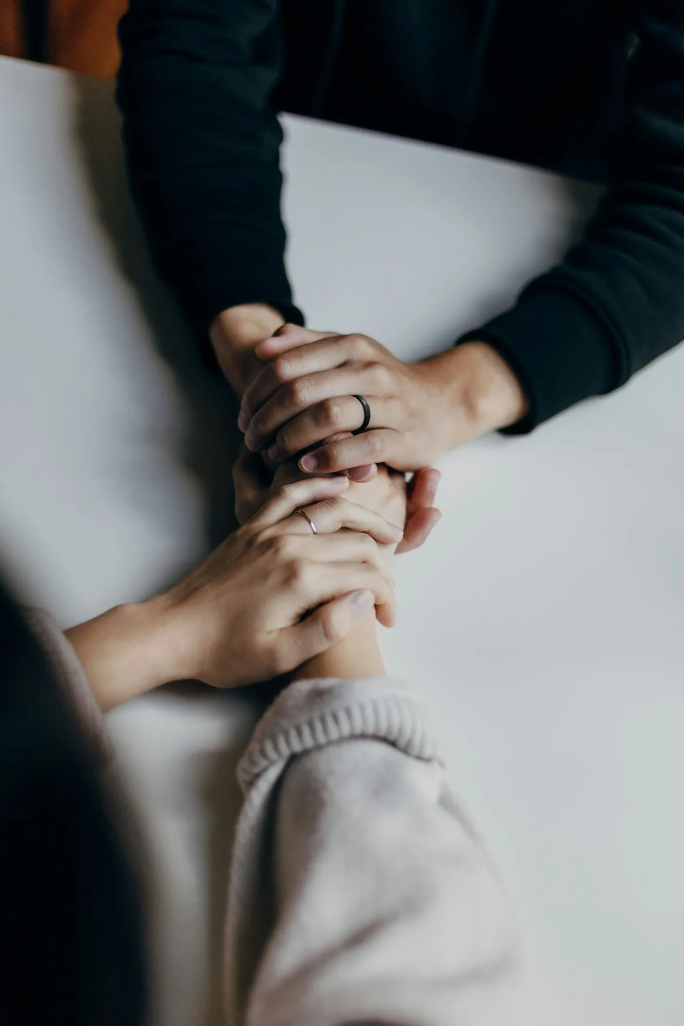 Two people holding hands across a table as a sign of support